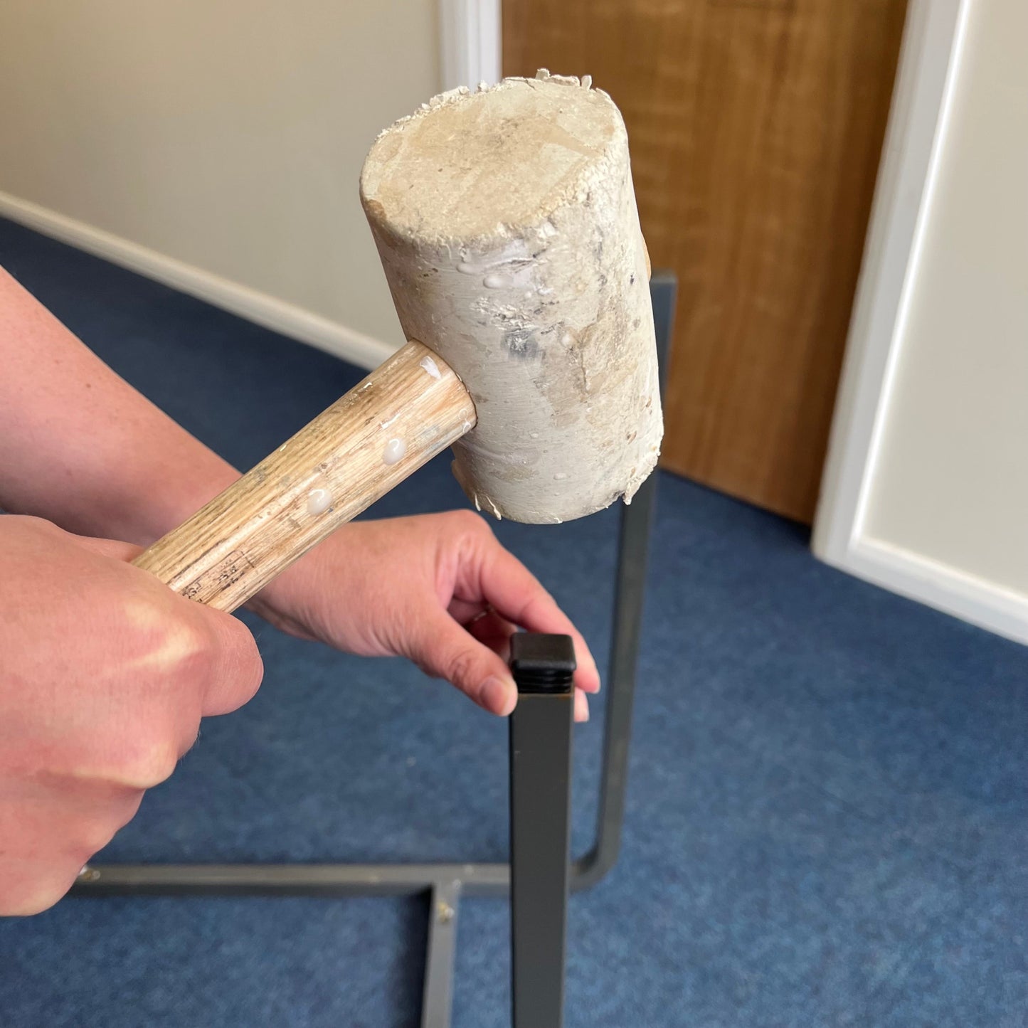 Rubber mallet hammering in square classroom table feet